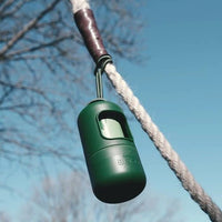 A green cylinder-shaped dog poop bag holder tied to a rope